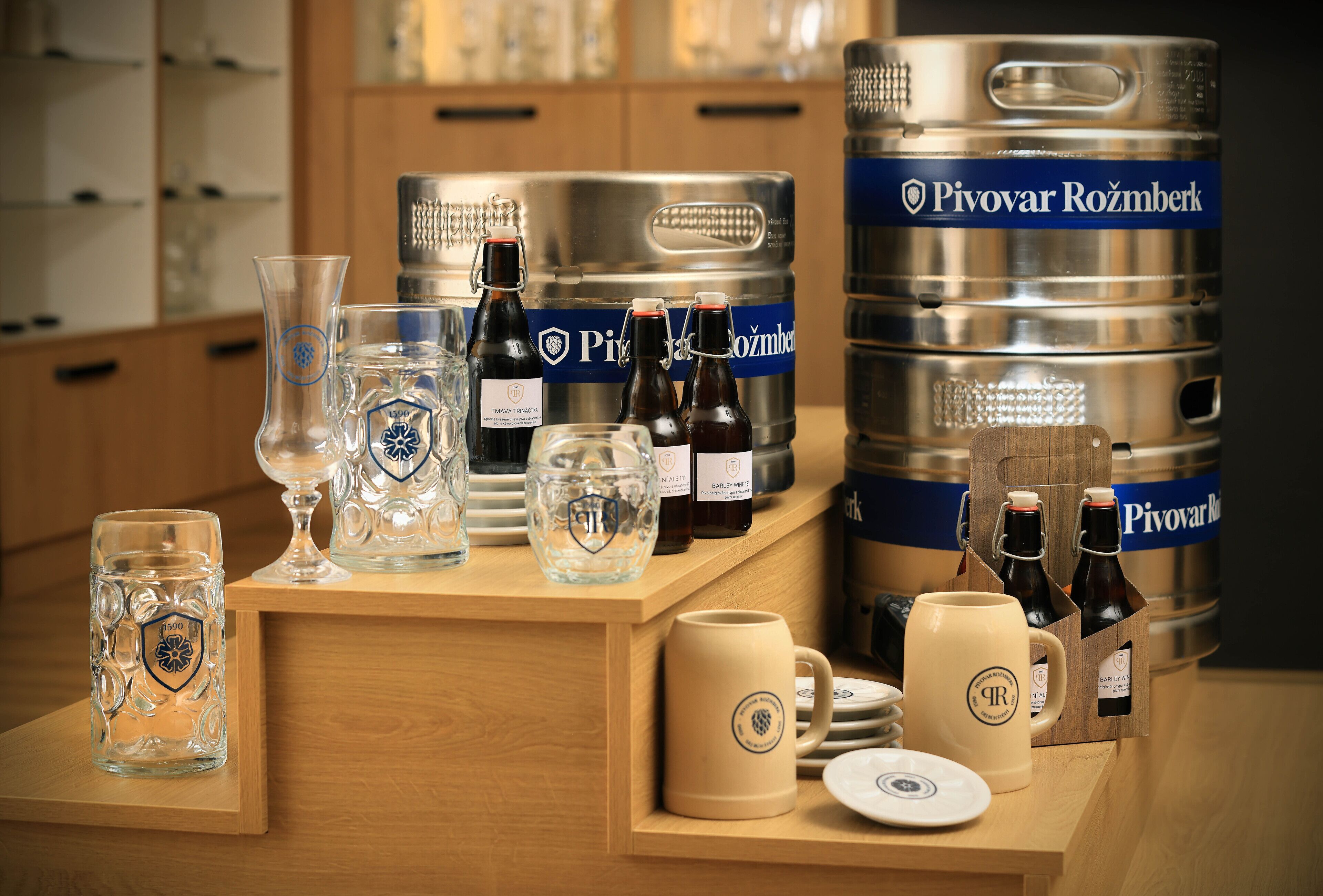 A bar area with various glassware, bottles, and a large keg labeled "Pivovar Rožmberk".