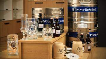 A bar area with various glassware, bottles, and a large keg labeled "Pivovar Rožmberk".