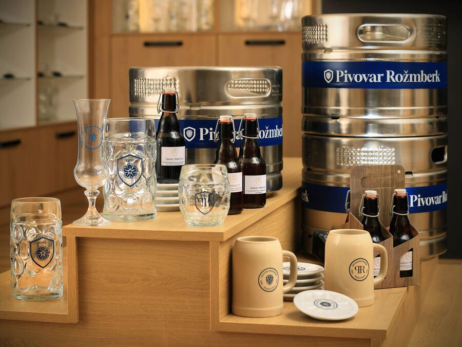 A bar area with various glassware, bottles, and a large keg labeled "Pivovar Rožmberk".