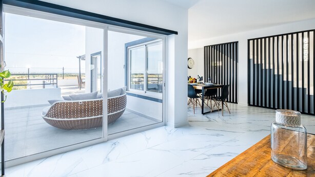 A modern interior with a large sliding glass door leading to a balcony, a dining area with a table and chairs, and a large window with a view of the outdoors. - Spacious Villa: Jacuzzi, Cinema & Heatable Pool (Pêra)