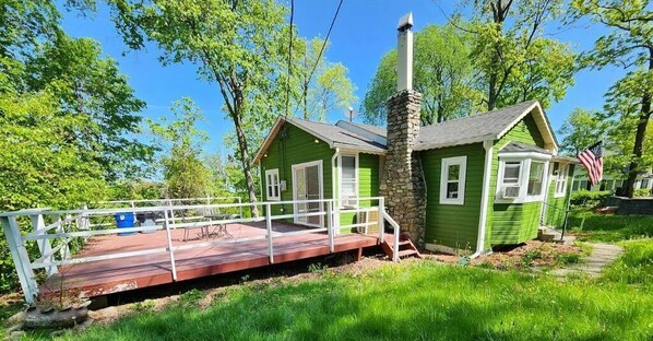 Surrounded by lush greenery, this charming house offers a peaceful retreat with a front porch and deck area.