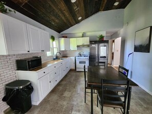 Compact kitchen with a dining area, featuring a refrigerator, microwave, and small dining table with two chairs.