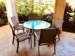 A round table with four chairs in a covered outdoor area with tiled flooring and surrounding greenery. - 3BR I Luxury Villa l Designer Furnishings, Central A/C (Koloa)