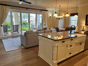 A modern kitchen with a central island, white cabinetry, and pendant lighting.