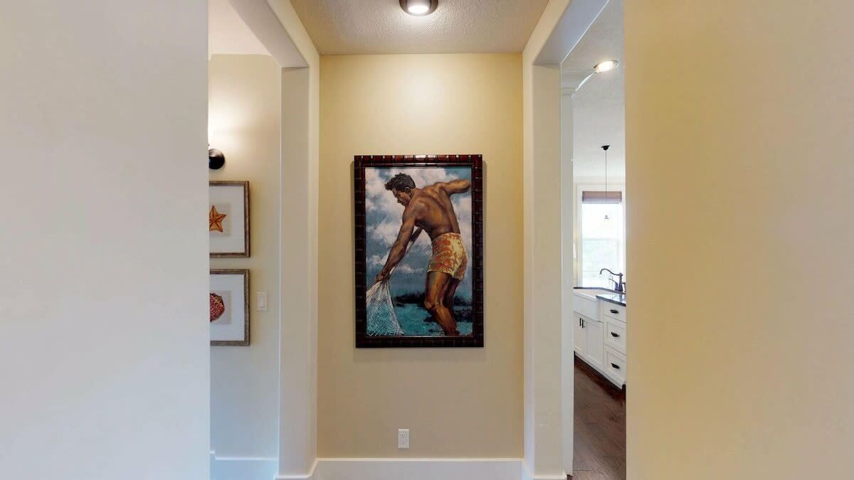 Un couloir avec un tableau encadré au mur, une décoration en forme d’étoile et un meuble blanc avec des tiroirs.