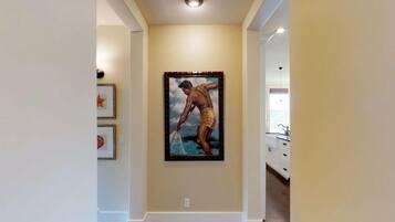 Un couloir avec un tableau encadré au mur, une décoration en forme d’étoile et un meuble blanc avec des tiroirs.
