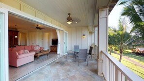 Ein offener Wohnbereich mit Sofa, Couchtisch und Esstisch, verbunden mit einem Balkon mit Gartenblick.