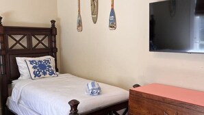 Un dormitorio con una cama de madera, un aparador y un televisor montado en la pared.