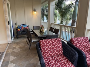 A covered patio area with a dining table and chairs, a wicker sofa, and a small cart with exercise equipment. - 3BR I Luxury in Paradise l Beaches, Golf, Shopping (Koloa)