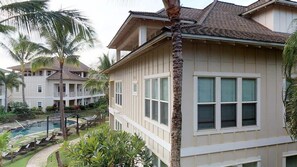 A multi-story hotel with a pool, palm trees, and a well-maintained garden. - 3BR I Poolside Lanai Villa l Parking, Sunset View (Koloa)