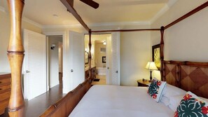 A four-poster bed with a wooden headboard, a nightstand with a lamp, and a mirror on the wall. - 3BR I Poolside Lanai Villa l Parking, Sunset View (Koloa)