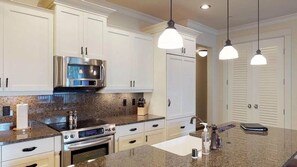 A modern kitchen with white cabinets, stainless steel appliances, granite countertops, and pendant lighting. - 3BR I Poolside Lanai Villa l Parking, Sunset View (Koloa)