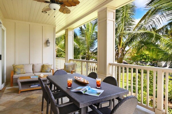A covered outdoor area with a dining table, chairs, and a sofa.