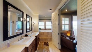 Un baño con un espejo grande, dos lavamanos, una bañera y una ventana.
