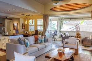 A spacious living area with a sofa, chairs, a coffee table, and a dining area with a kitchen in the background.