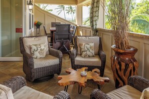 A covered outdoor seating area with wicker furniture and a wooden coffee table.