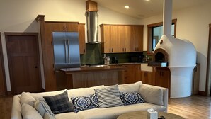 Una sala de estar moderna con un sofá seccional, una mesa de centro redonda y una cocina con armarios de madera y horno empotrado.
