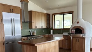 Una cocina moderna con armarios de madera, electrodomésticos de acero inoxidable y un horno para pizza empotrado.