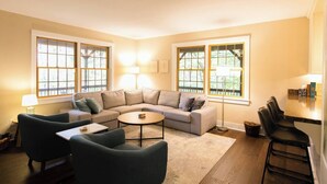 Una sala de estar con un sofá modular, una mesa de centro y un comedor con sillas.