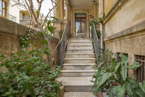 A stone staircase leading to a door with a small table and chairs outside. - Cavour Apartments by Wonderful Italy (Noto)