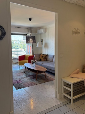Un salon avec un canapé, une table basse, une lampe et une vue par la fenêtre.