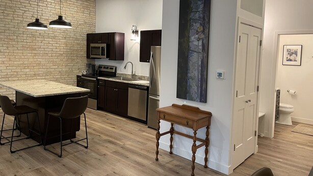 A modern kitchen with a central island, dark cabinets, and pendant lighting. - 15 minutes to EAA. Newly renovated, Luxury 1 Bedroom in historic downtown Neenah (Neenah)