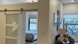 A modern living room with a sliding glass door leading to a bedroom. There is a sofa, a lamp, and a rug on the floor. - 15 minutes to EAA. Newly renovated, Luxury 1 Bedroom in historic downtown Neenah (Neenah)