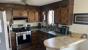 Una cocina con armarios de madera, estufa de acero inoxidable, un lavamanos y encimera de madera.