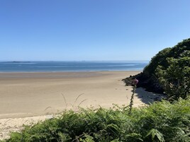 Una playa con cielo despejado, mar tranquilo y acantilados rocosos.