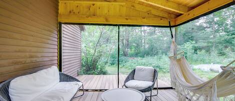 Relax on the deck with a hammock, two comfortable chairs, and a round table, surrounded by lush forest views.