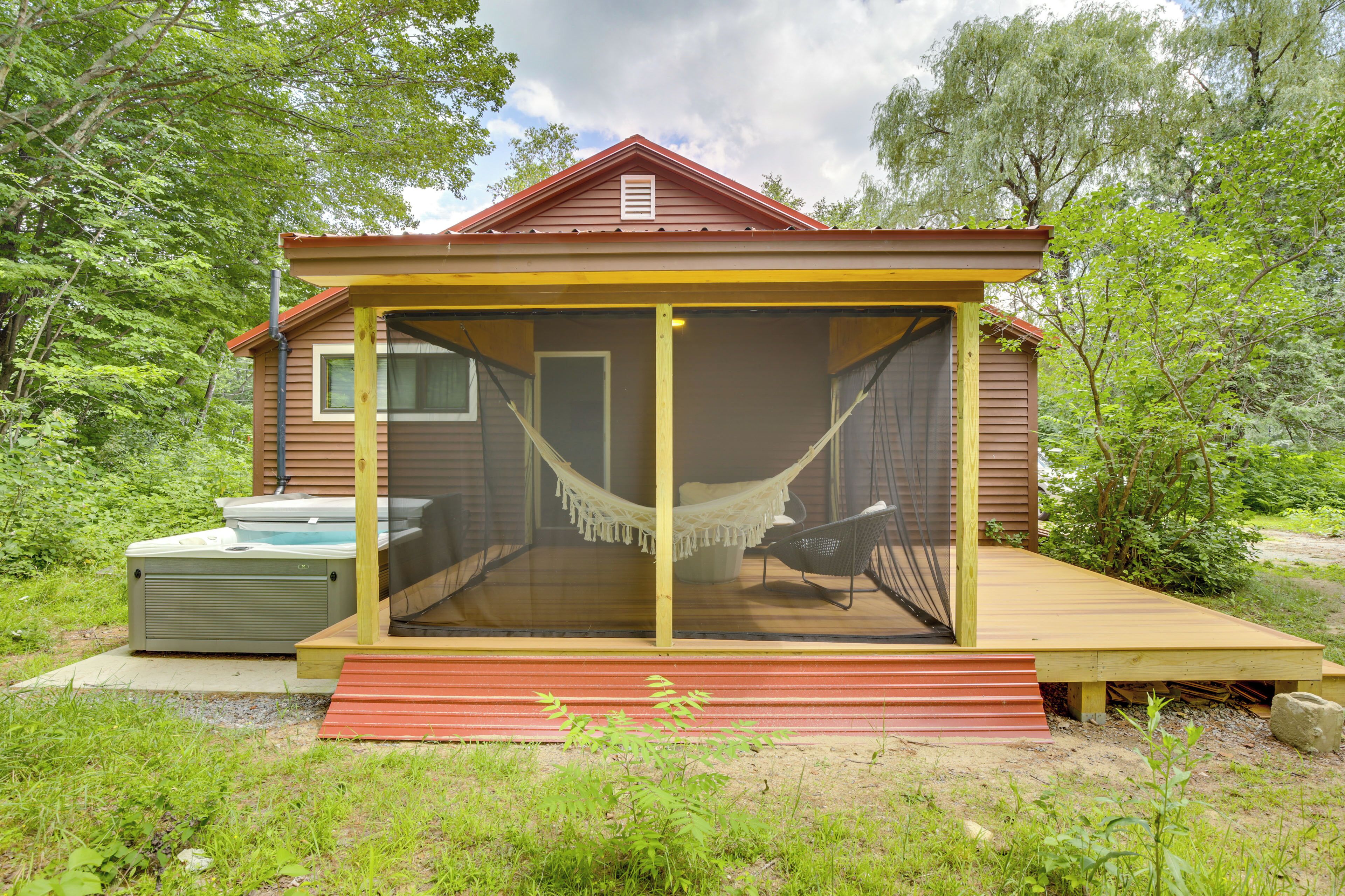 Une cabane en bois avec une véranda grillagée, un hamac et un bain à remous.
