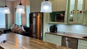A modern kitchen with a wooden island, stainless steel appliances, and pendant lighting.