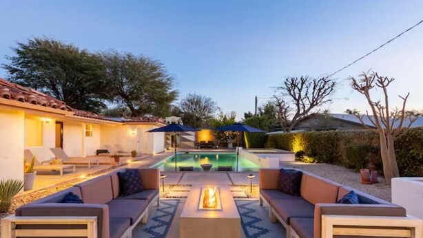 A poolside area with a fire pit, outdoor seating, and umbrellas. - Casa Bermuda a Spanish Boho Retreat, Expansive Pool/Spa Pet Friendly (Bermuda Dunes)