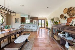 Une cuisine spacieuse avec une longue table en bois, des tabourets de bar et un îlot central.