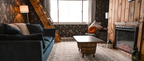 Une pièce chaleureuse avec un canapé bleu, une table basse en bois et une cheminée.