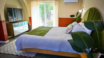 Une chambre à coucher avec un lit, une télévision, une fenêtre avec des rideaux et une plante.