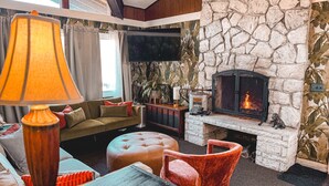 Ein gemütliches Wohnzimmer mit Kamin, bequemen Sitzmöglichkeiten und einem Fernseher.