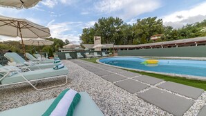 Ein Poolbereich mit Liegestühlen, Sonnenschirmen und einem Schwimmbecken.