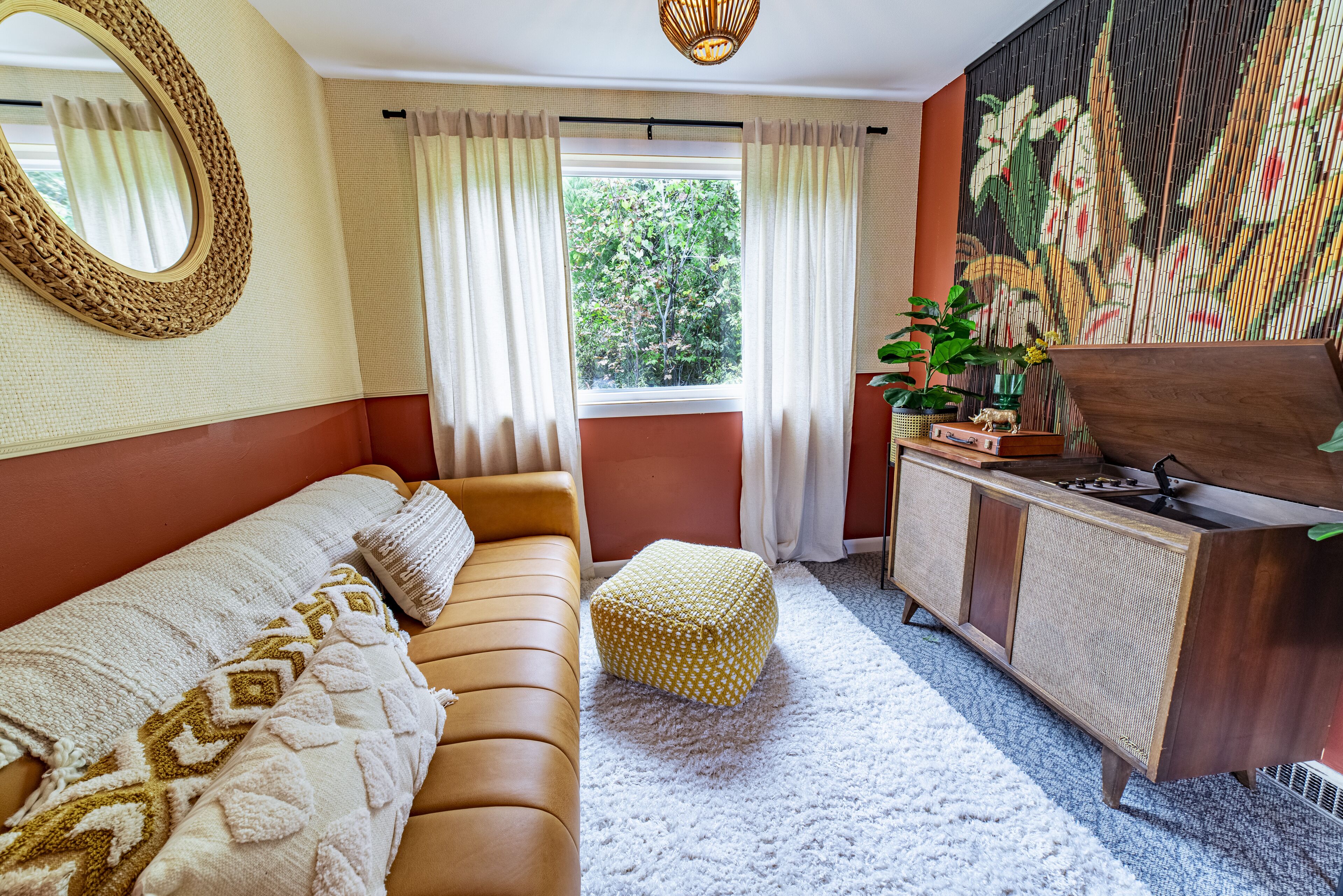 Una habitación con un sofá marrón, un tapete blanco, un armario de madera y una ventana con cortinas.