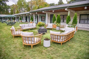 A patio area with outdoor furniture, a fire pit, and potted plants. - The Springs Motel (New Ashford)