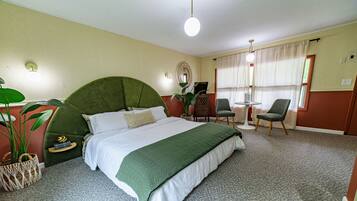 A neatly arranged bedroom with a large bed, bedside tables, a desk, and a chair.