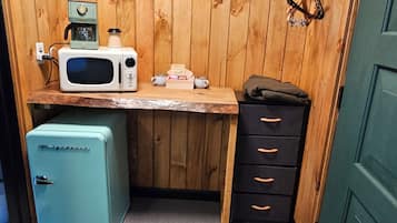 Una kitchenette compacta con microondas, cafetera y refrigerador pequeño.