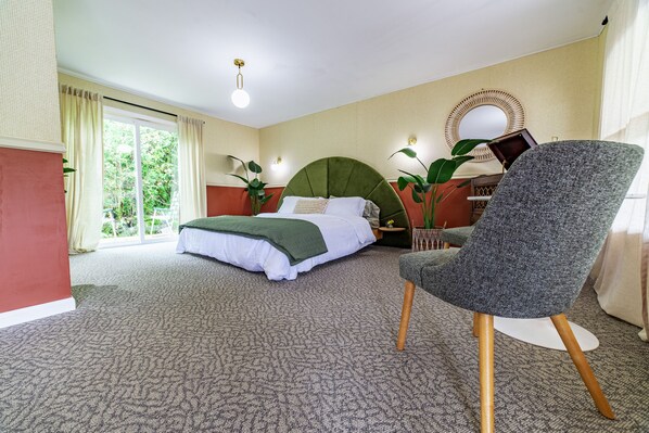 A bedroom with a bed, a chair, a nightstand, and a window with curtains. - The Springs Motel (New Ashford)