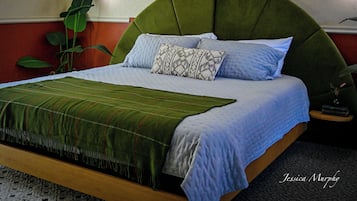 A bed with a green upholstered headboard, a patterned pillow, and a green blanket.