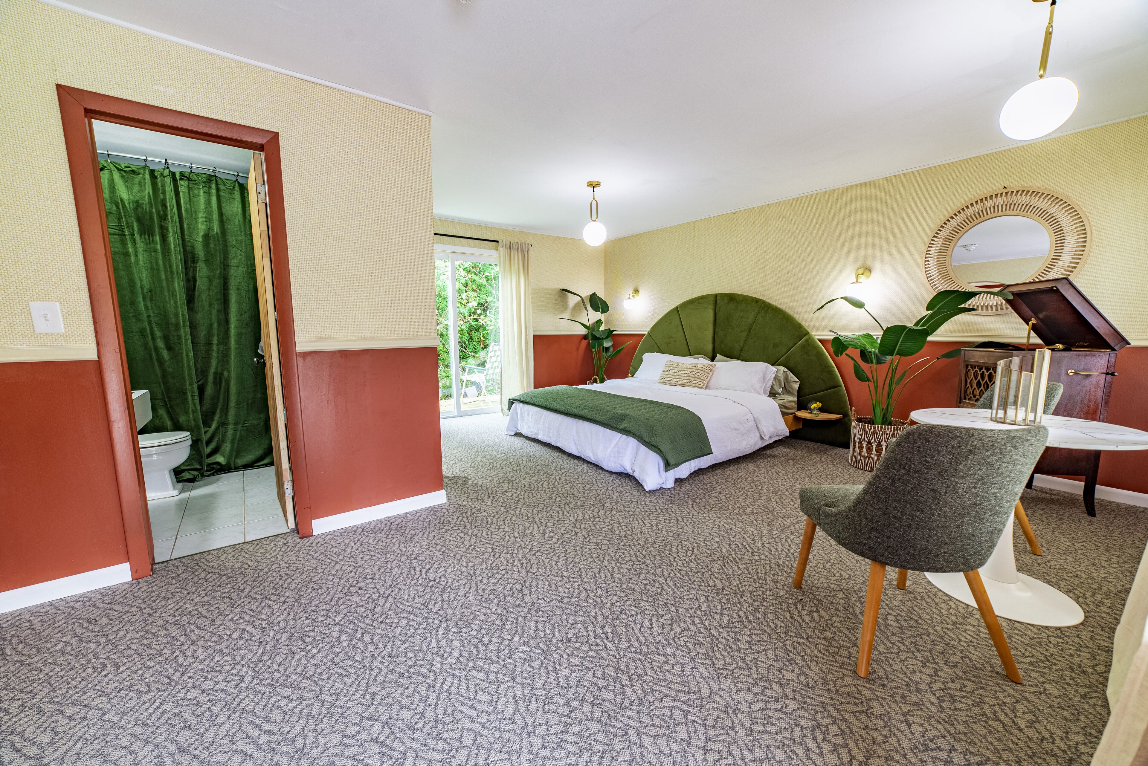 A hotel room with a bed, a chair, a table, and a mirror.