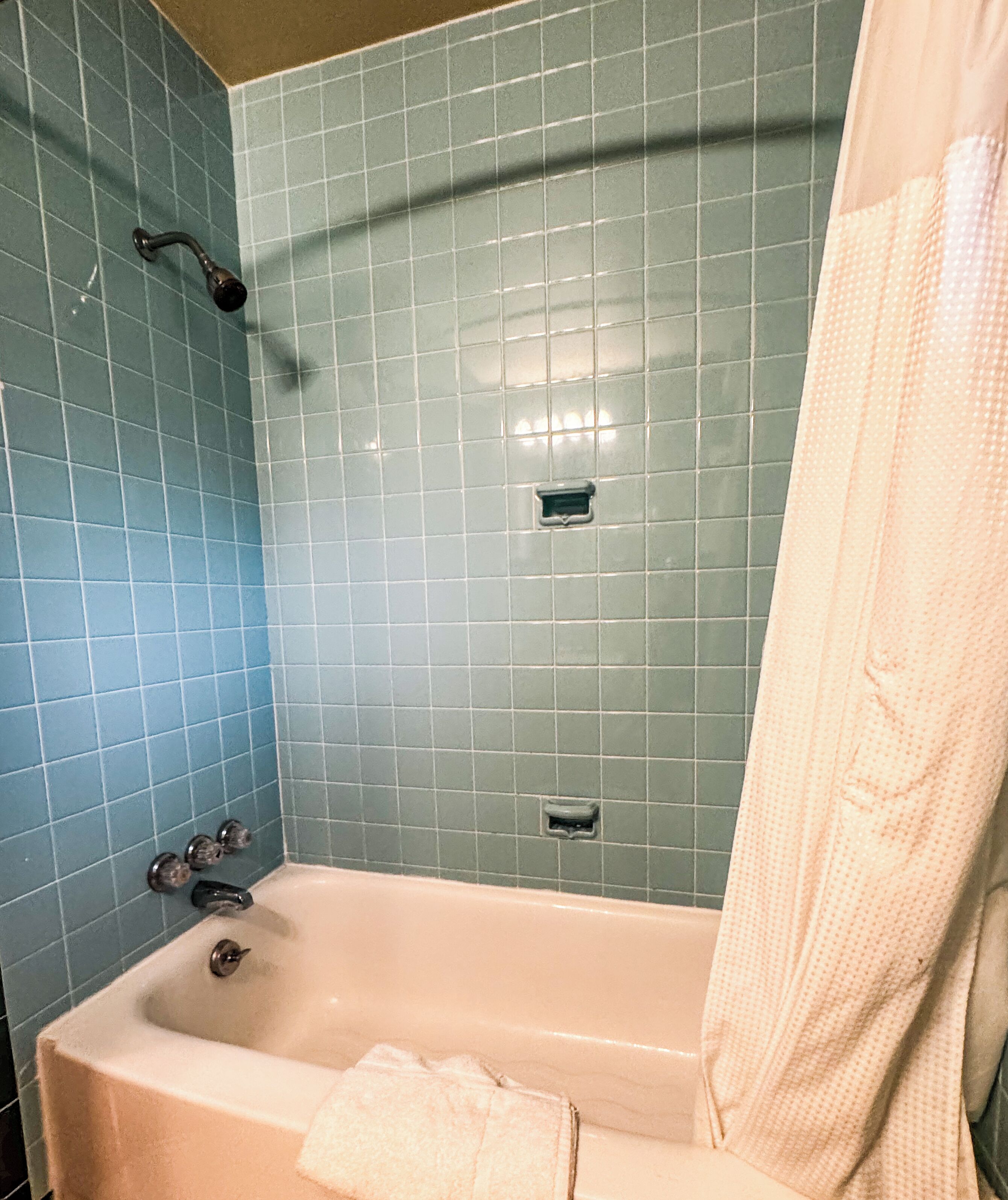 A bathroom with a bathtub, a shower, and a towel rack.