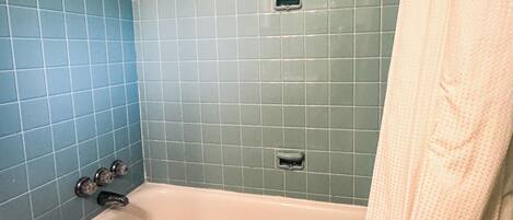 A bathroom with a bathtub, a shower, and a towel rack.
