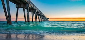 A pier extending into the ocean with a sunset in the background.