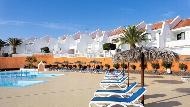 A pool area with lounge chairs and a building with white walls and red roofs. - Home2Book Stylish Apt Pool & Terrace, Sand Club (Oasis del Sur)