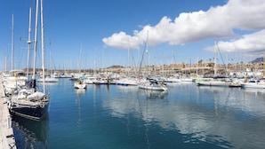 A marina with multiple sailboats docked, calm water, and a distant town. - Home2Book Stylish Apt Pool & Terrace, Sand Club (Oasis del Sur)